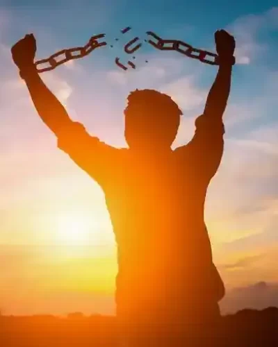 A person breaking from chains, symbolizing hope and recovery from addiction. A bright light shines in the background, representing a new path forward. The image convey a message of power of resilience and empowerment, encouraging individuals struggling with substance abuse to seek help. the overall tone is uplifting, inspiring individuals to overcome addiction and find solace in expert Nasha Mukti Kendra in Delhi NCR.